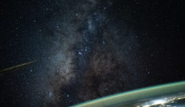 The Milky Way galaxy appears above Earth's greenish atmospheric glow. The galaxy's dust and stars can be seen against the darkness of space.