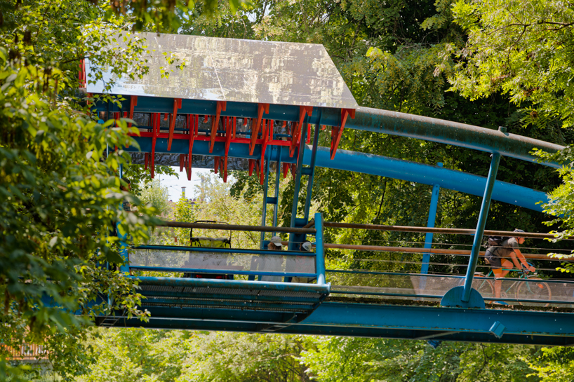 coral-toned timber and mirror canopy by GRRIZ transforms footbridge above river in france