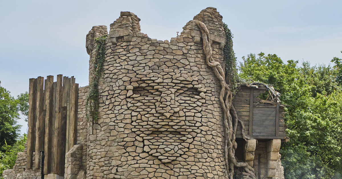 kinetic sculpture outlines moving face onto tower's stonework in french theme park