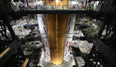 Image shows orange rocket stage with two large solid rocket boosters stacked alongside on March 23.