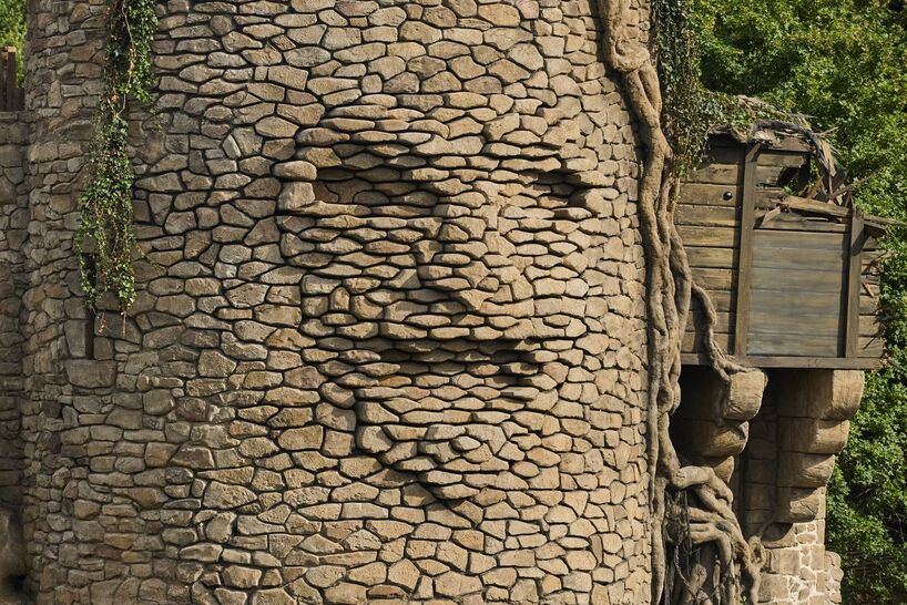 kinetic sculpture outlines moving face onto tower's stonework in french theme park