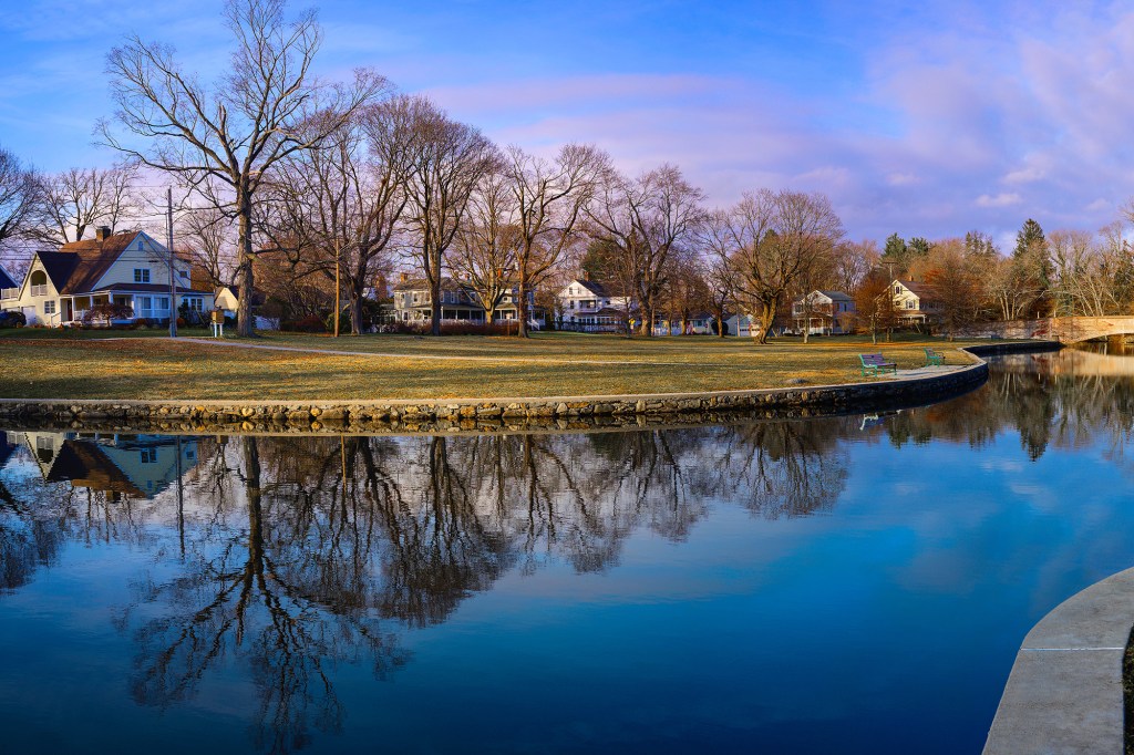 New England houses reflected in a calm river.
