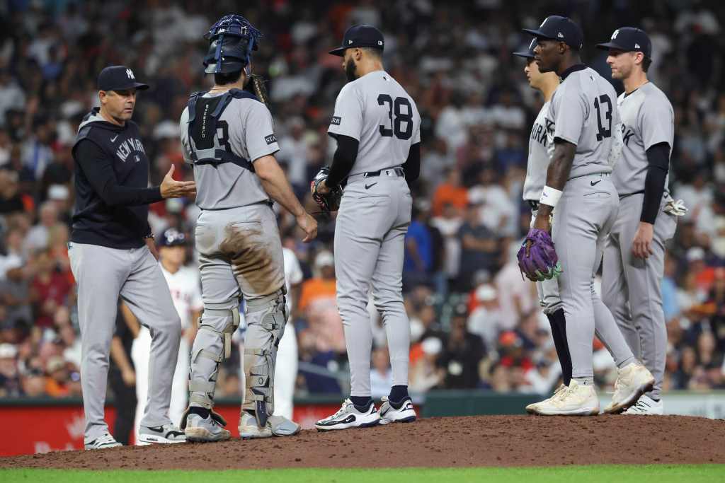 New York Yankees manager Aaron Boone and players confer on the pitcher's mound.