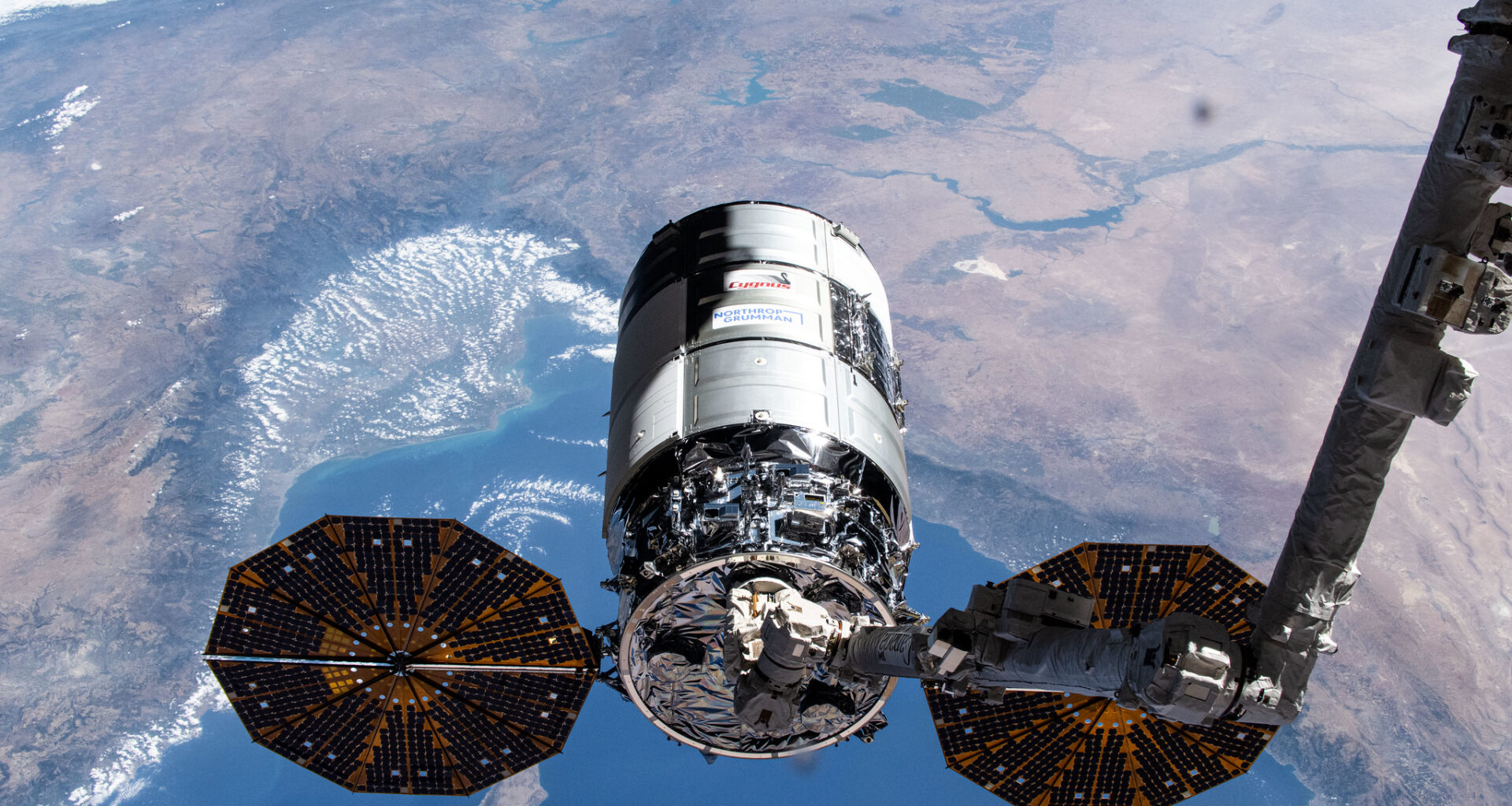 Northrop Grumman's 21st Cygnus cargo craft, with its prominent cymbal-shaped UltraFlex solar arrays, is pictured in the grips of the Canadarm2 robotic arm shortly after its capture on Aug. 6, 2024.