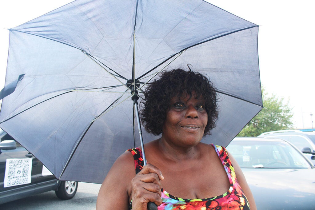 A woman stands underneath an umbrella