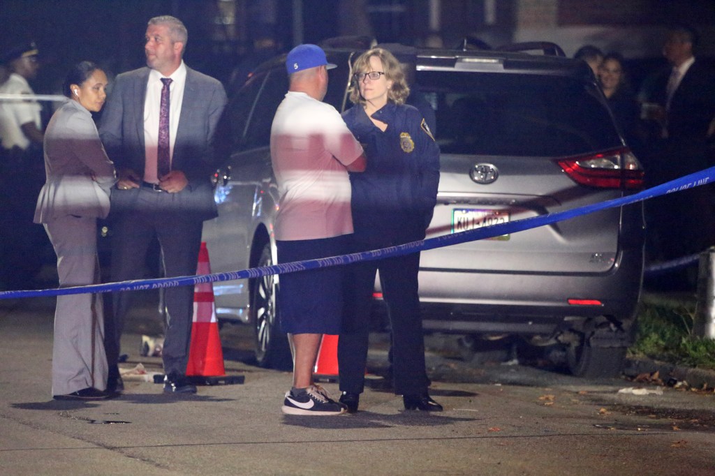 NYPD officers investigating a shooting at night, with blue police tape across the foreground.