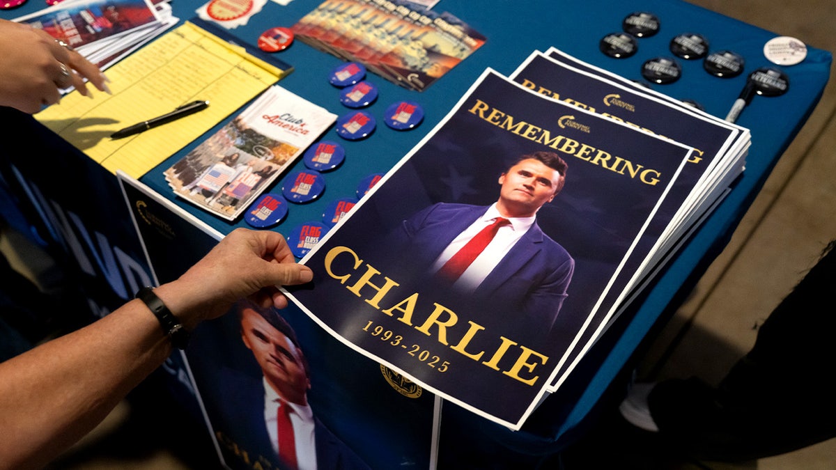 A 'Remembering Charlie Kirk' graphic sitting on a table with other Turning Point USA content