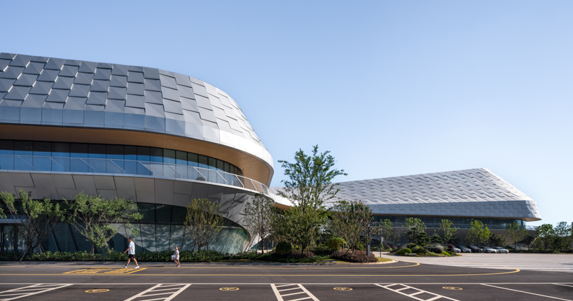 scale-like facade wraps hushan swimming center's undulating form by LYCS architecture