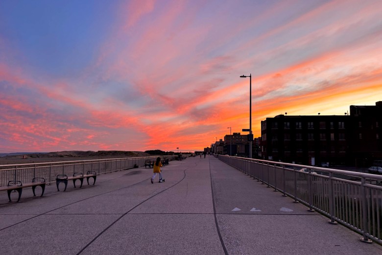 The sun sets over the Rockaway Beach boardwalk.