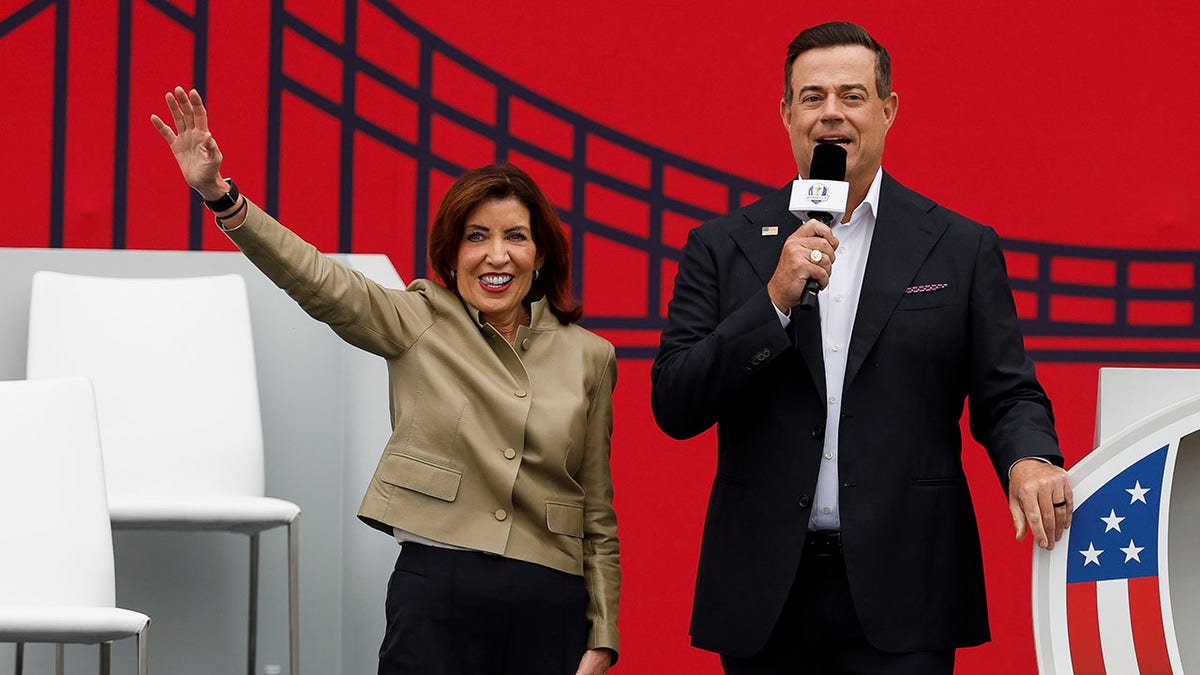 Kathy Hochul waves to the crowd with Carson Daly