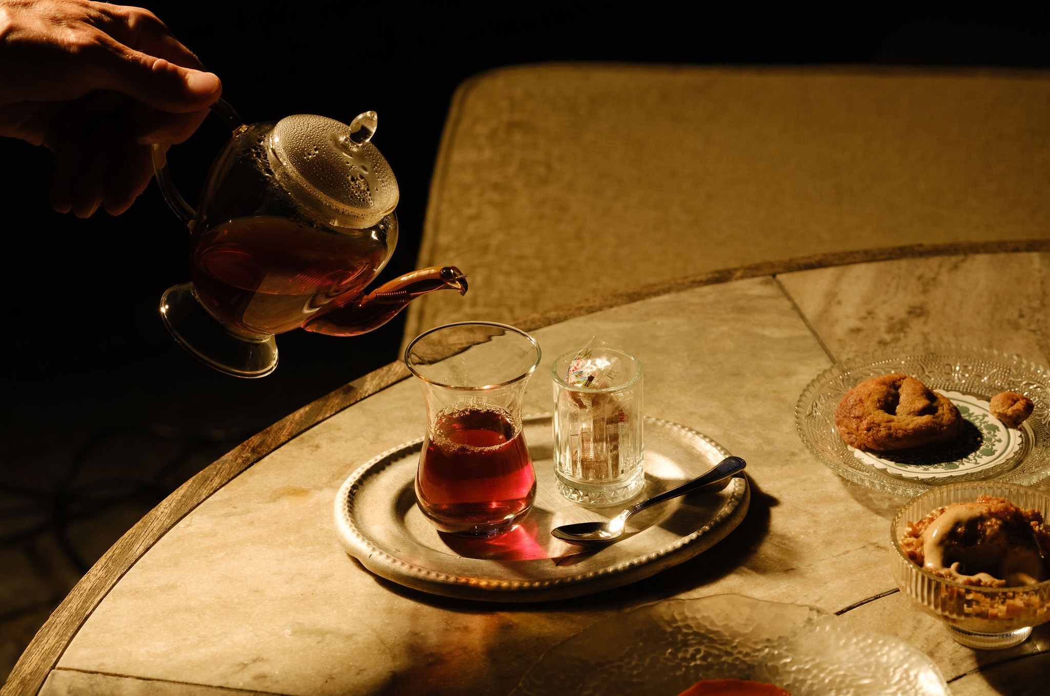 Outstretched hand pouring tea into a cup.