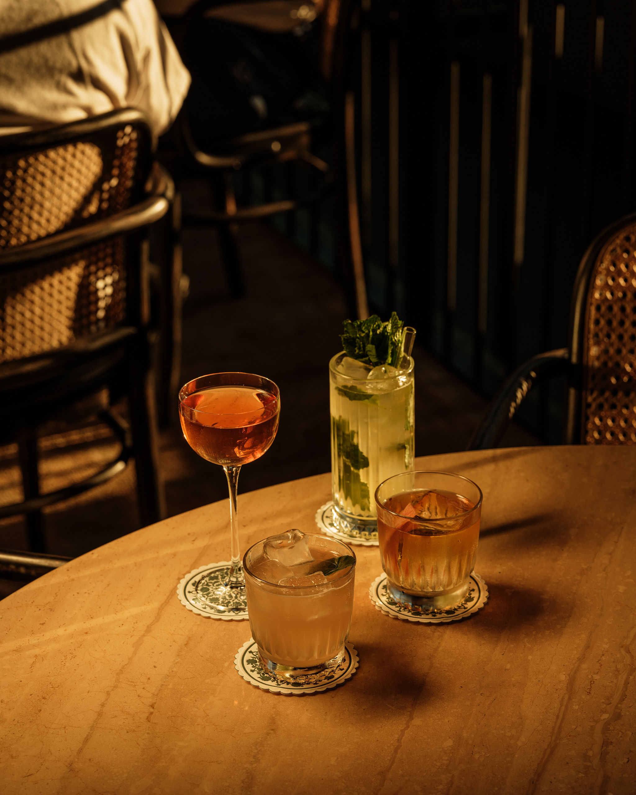 Drinks spread on a wooden table in a dimly lit room.