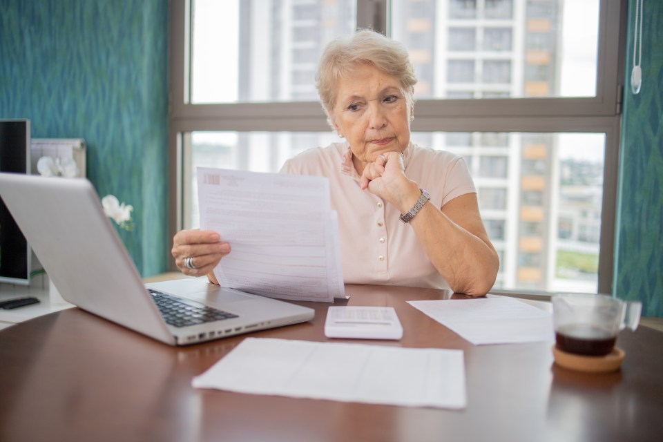 Senior woman paying bills at her home.