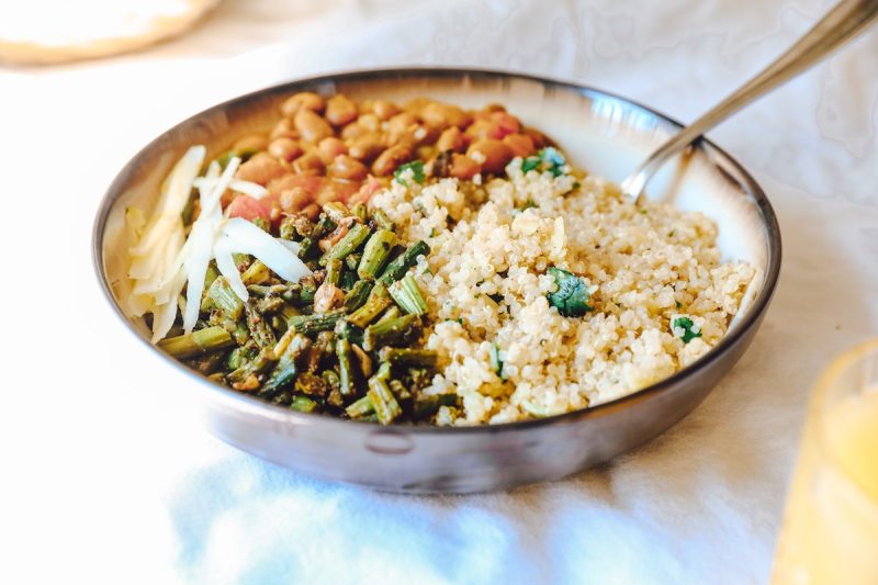 A quinoa-based dish with pinto beans and asparagus served in a bowl with a spoon