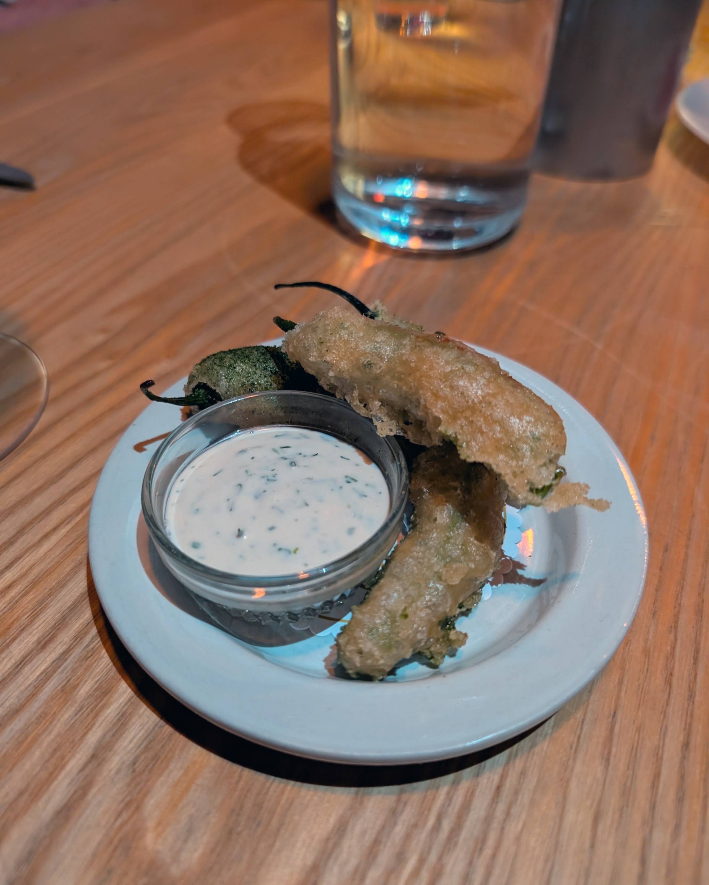 A plate of fried peppers with a creamy white sauce.