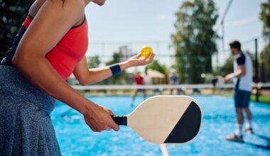 A woman holding a black and white paddle about to hit a yellow ball