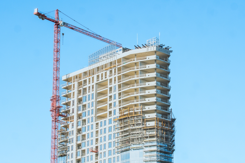 A crane building a tall building with blue sky in the background
