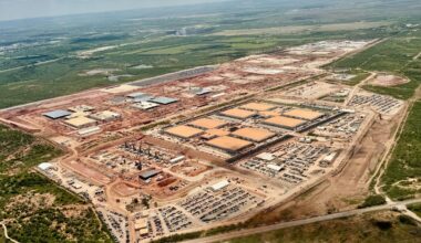 Aerial view of a sprawling data center facility under construction, with wide open West Texas landscape in the background