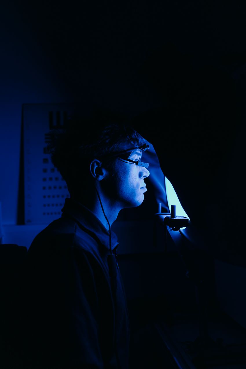 A person sitting in a dark room with one source of light in front of them.