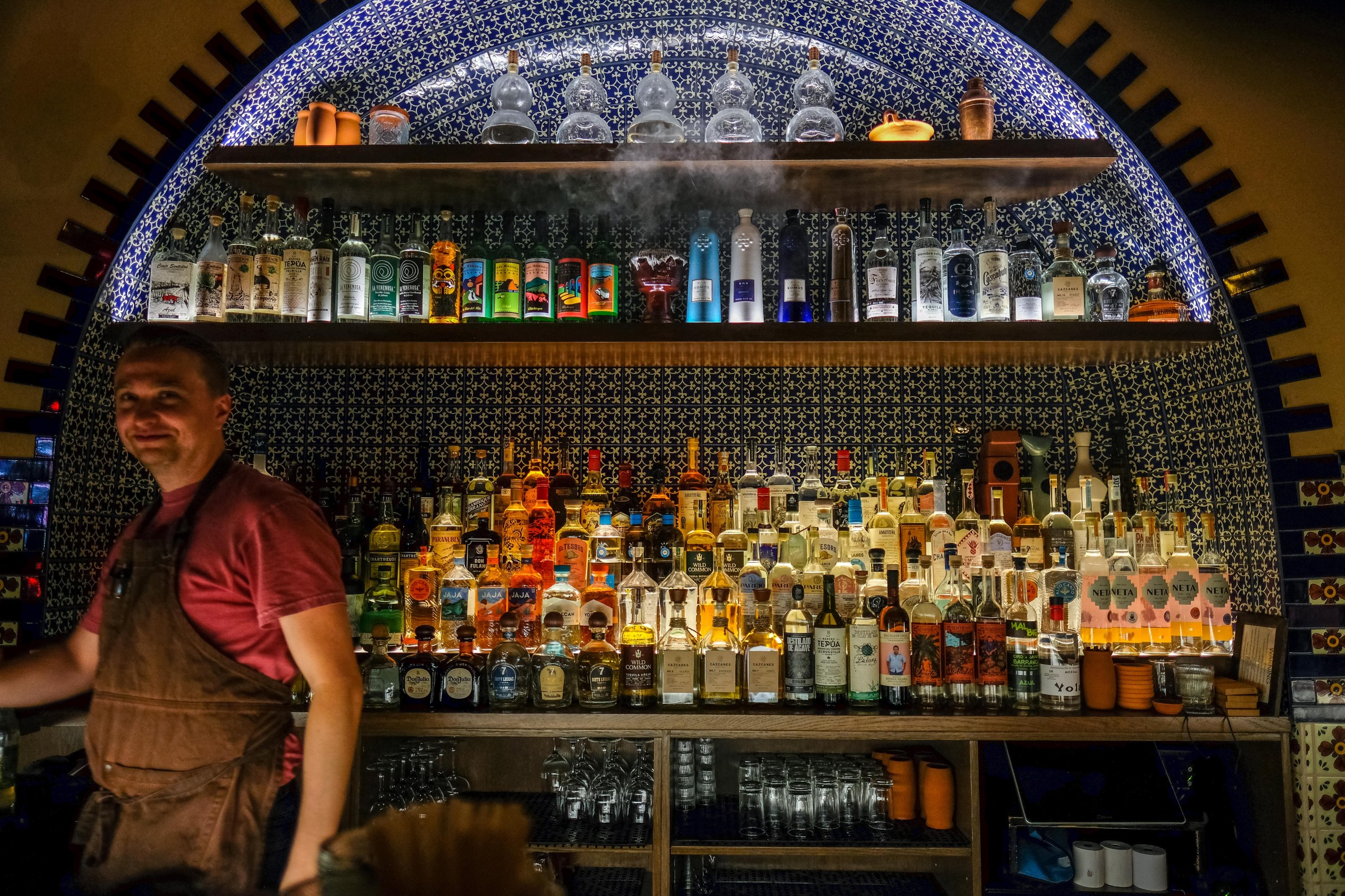 A bartender standing in front of a bar.