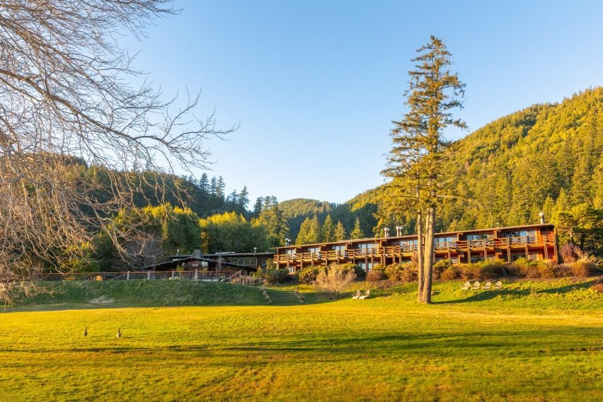 1970s lodge with a grassy meadow in front and forested mountains behind