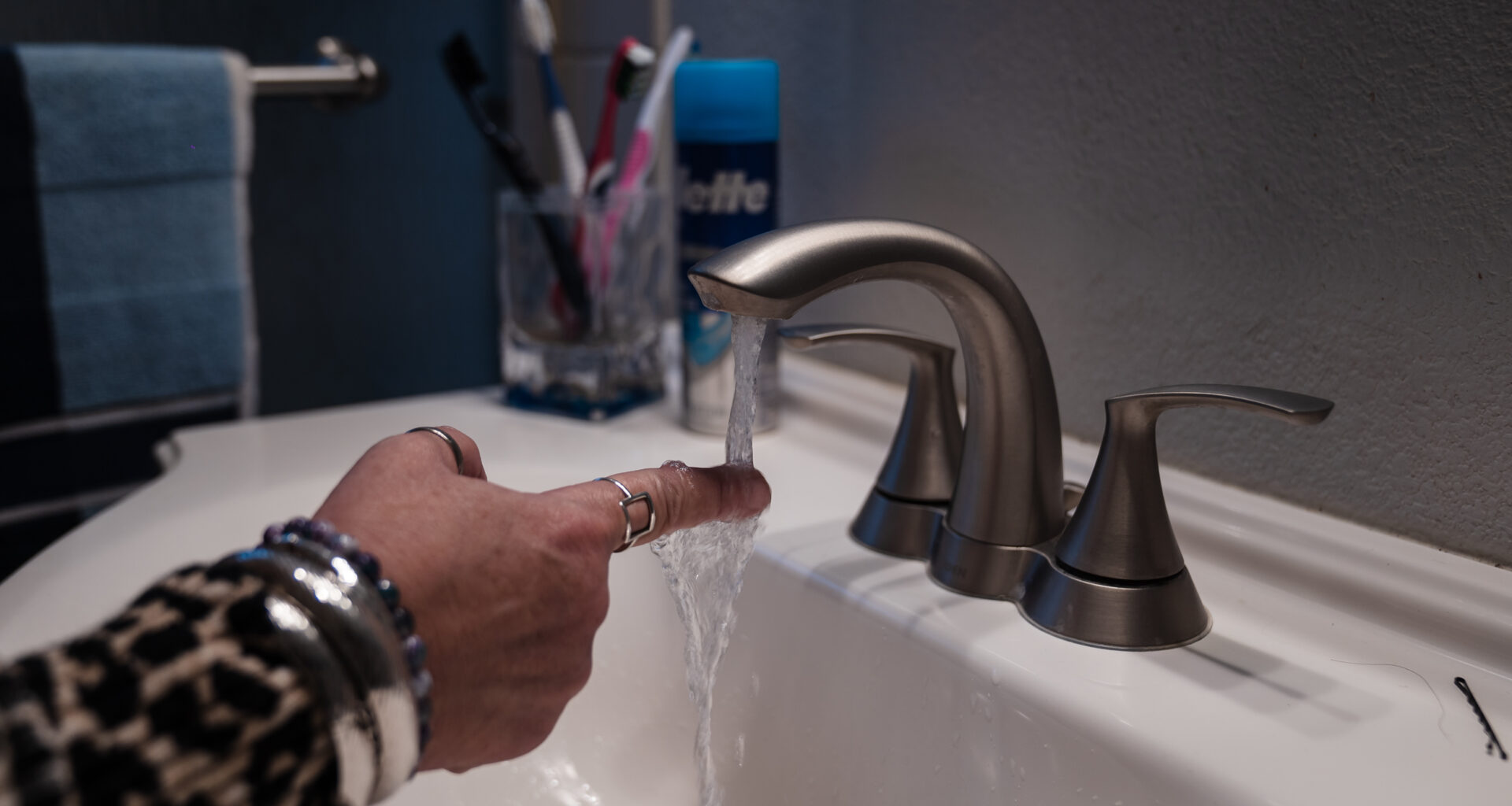 Teresa Morse sticks her hand under the faucet in her bathroom in Golden Hill on March 10, 2023. Morse says it can take several minutes to get warm water.