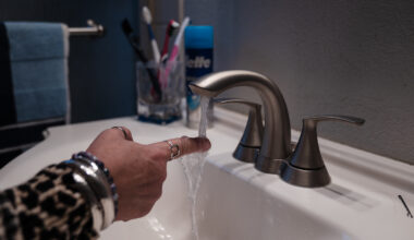 Teresa Morse sticks her hand under the faucet in her bathroom in Golden Hill on March 10, 2023. Morse says it can take several minutes to get warm water.
