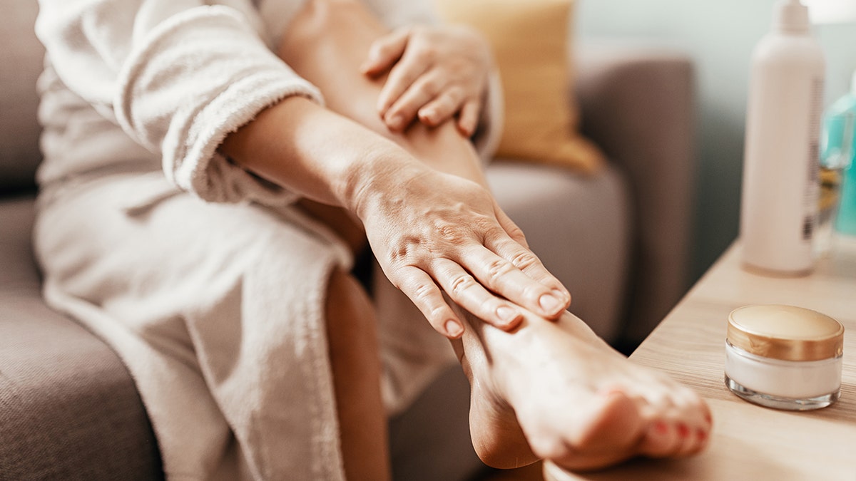 woman putting lotion on feet
