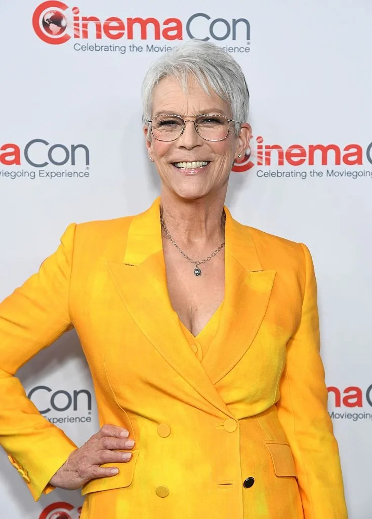 Person in a stylish suit at CinemaCon event, smiling and posing confidently for the camera