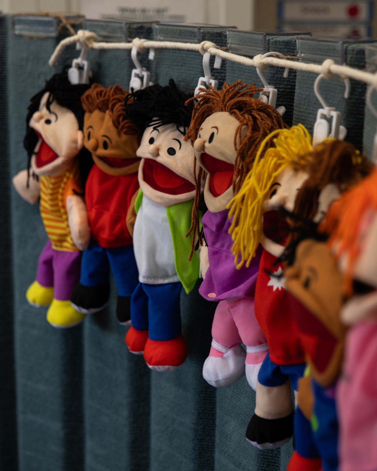 A row of puppets depicted as children hangs against a wall.