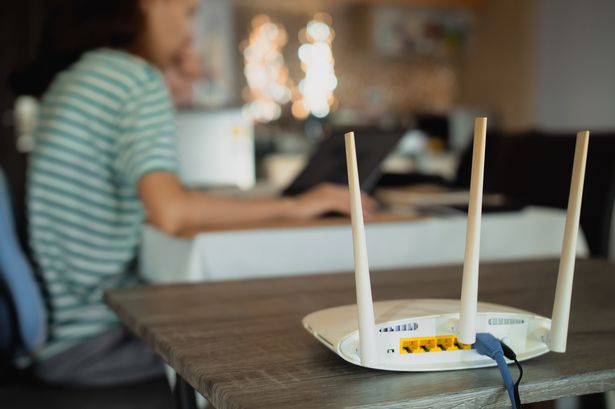 A woman is working at home using a modem router, connecting the Internet to her laptop