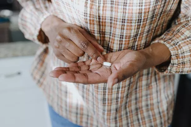 Close-up of unrecognizable woman holding a single pill in the palm of her hand