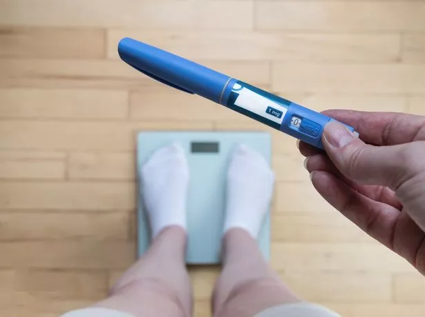 Ozempic Insulin injection pen for diabetics and weight loss. Woman weighs herself and holds Ozempic in her hand.