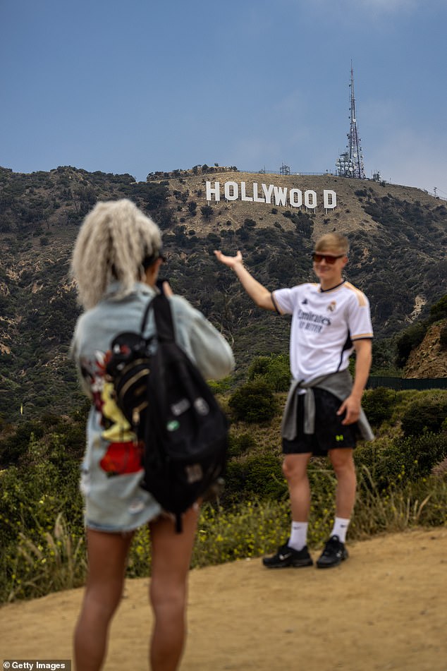 Visitors to California slumped over the summer. People take photos with the iconic Hollywood sign
