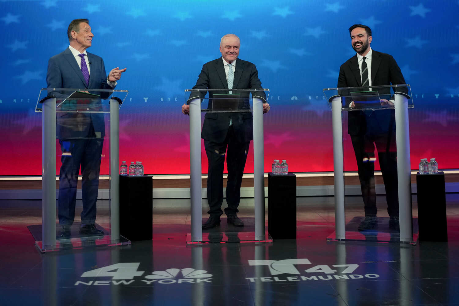 From left, Andrew Cuomo, Curtis Sliwa and  Zohran Mamdani seem to share a light moment on the debate stage.