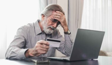 Worried senior man holding credit card