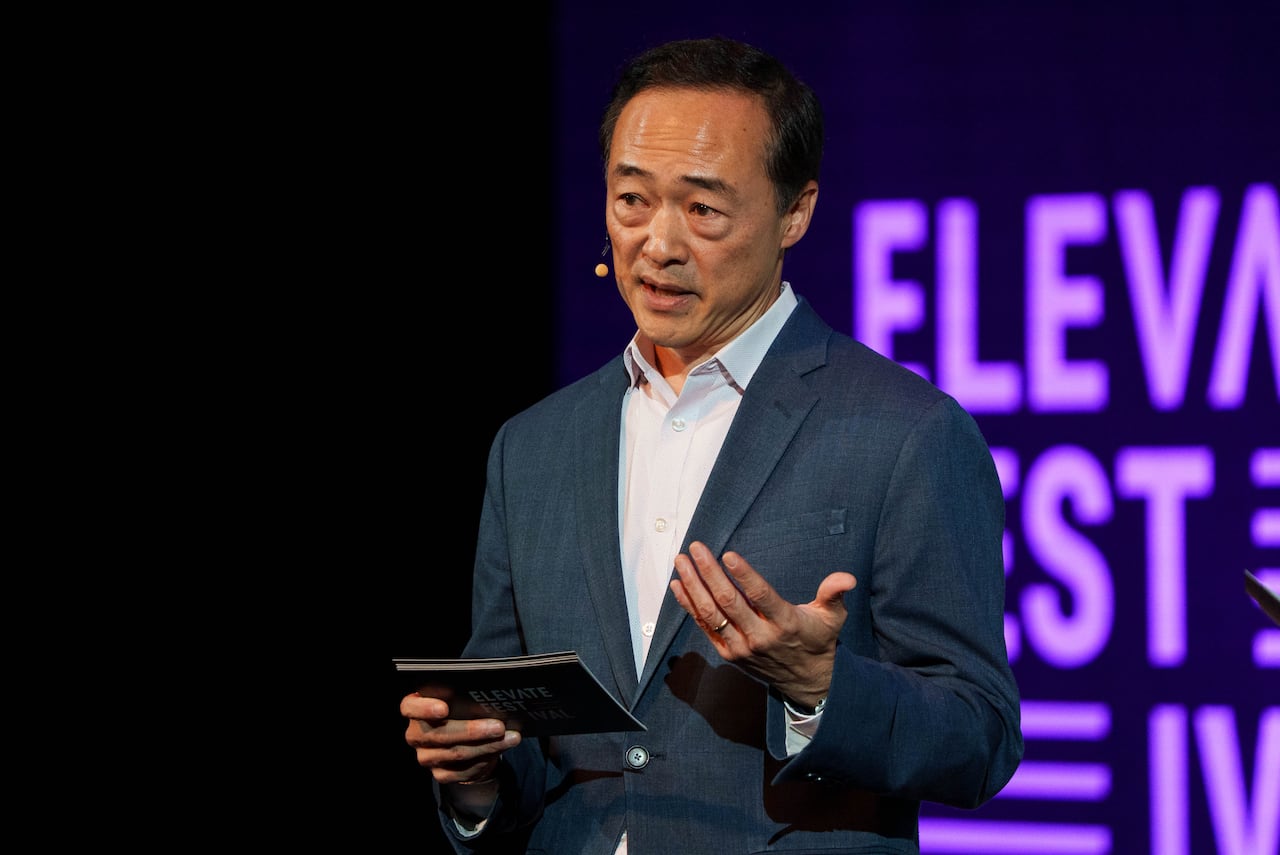 A man wearing a suit speaks on a stage.