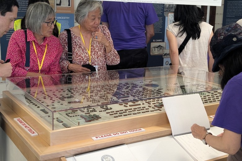 Pilgrims to the Crystal City event examine a model of the camp at a museum.
