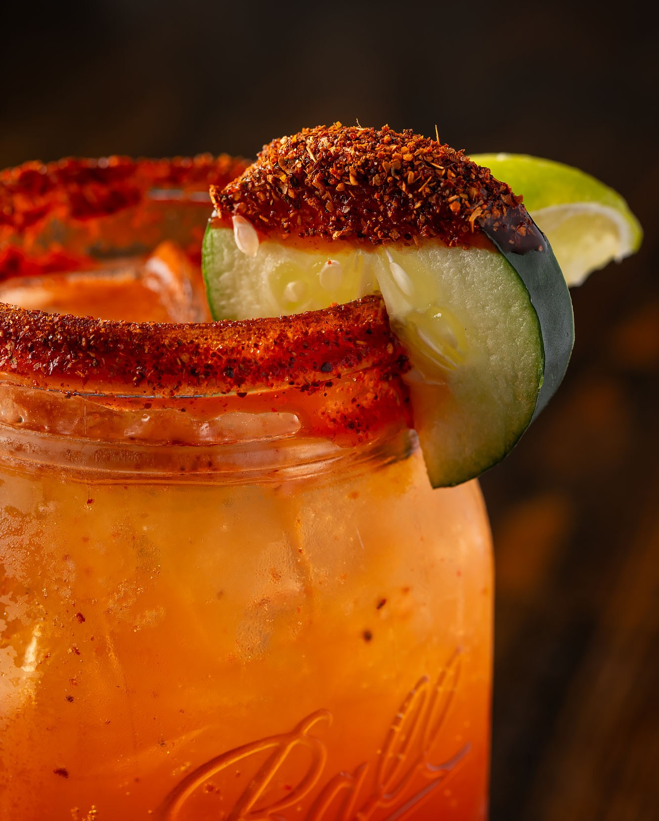 A refreshing Mexican beer drink called a Michelada with a Tajin-covered cucumber on the rim of the jar.