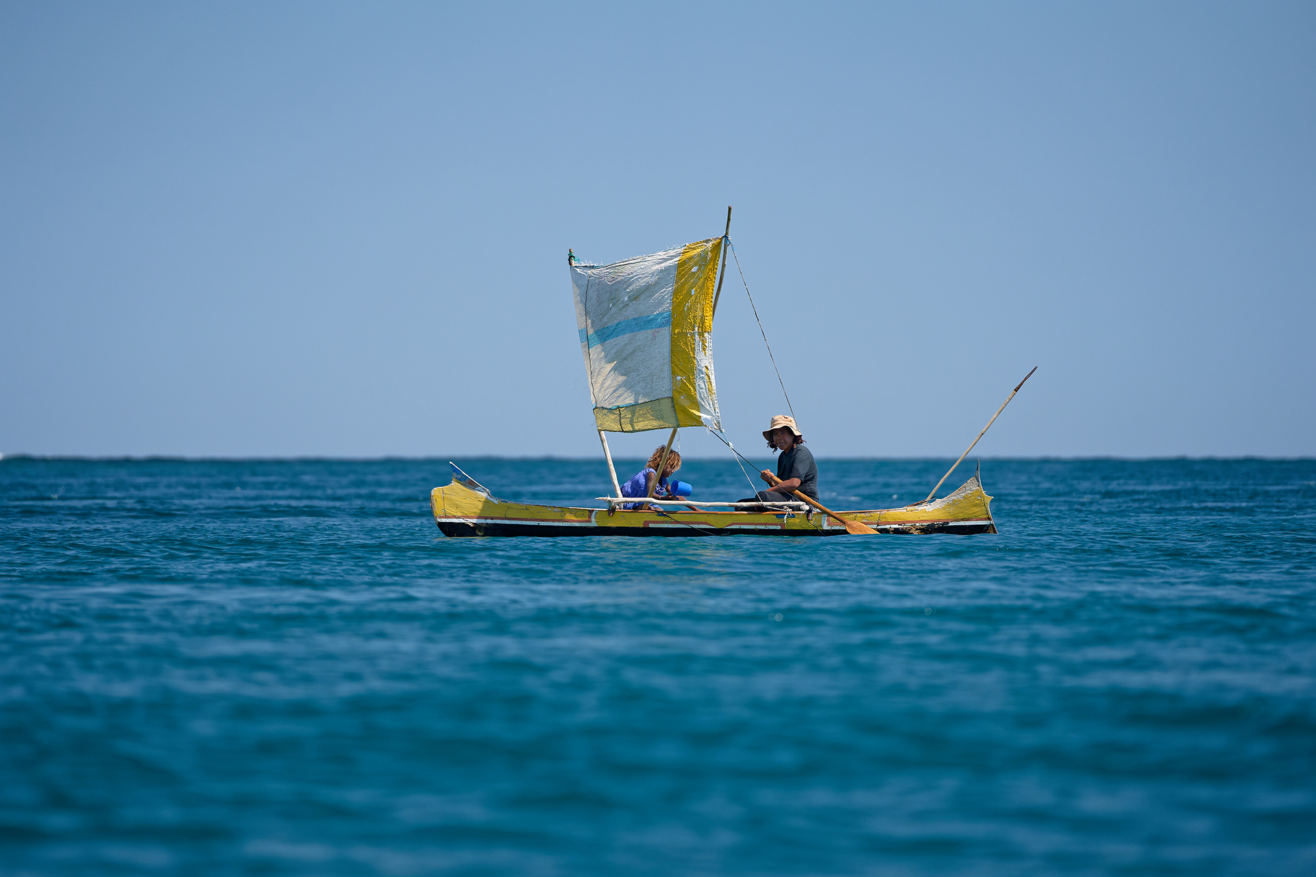 A woman and her granddaughter sailing in a yellow pirogue.