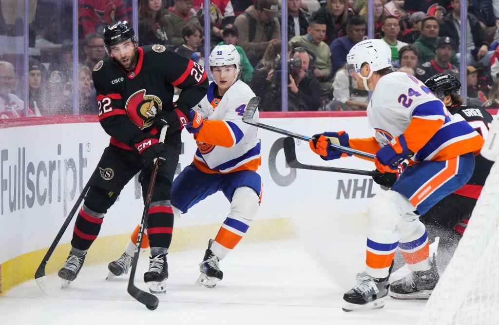 Islanders defensemen Matthew Schaefer (48) and Scott Mayfield (24) defend the Senators' Michael Amadio (22) on Oct. 18, 2025.