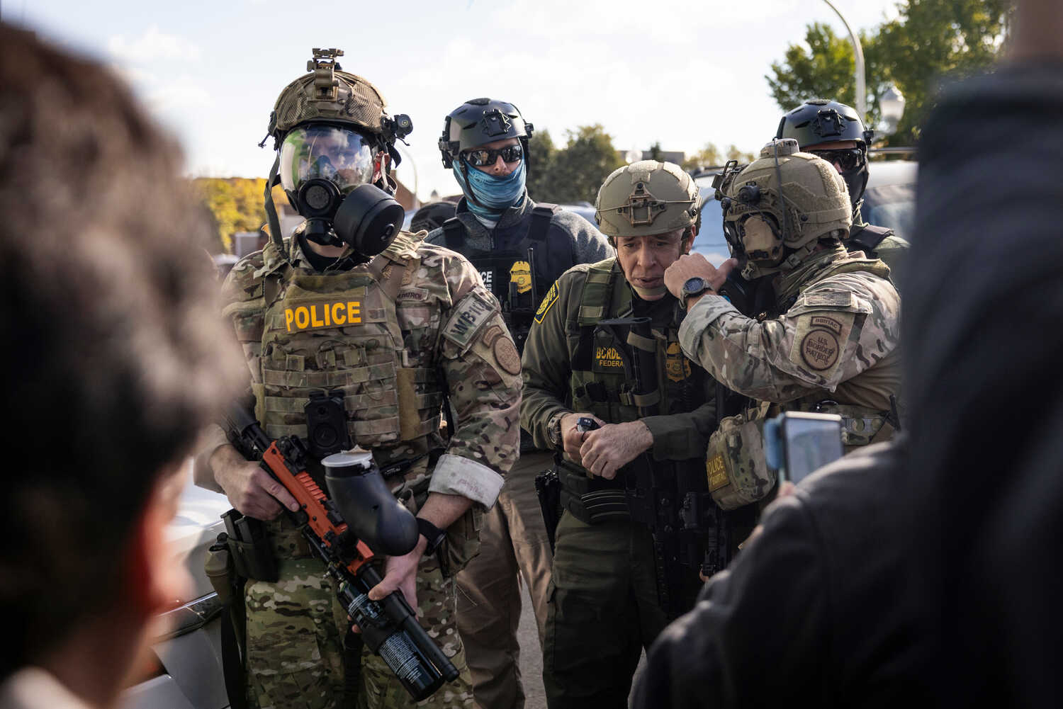 Men in camouflage uniforms, masks and helmets stand near Gregory Bovino, a senior Border Patrol official.