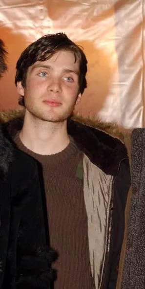 Four people posing indoors, wearing casual and semi-formal jackets