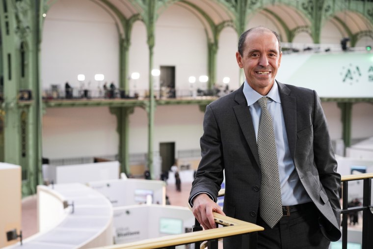 Chris Lehane leans on a metal balcony rail and smiles for a portrait