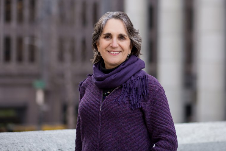 Judith Bell stands outside and smiles