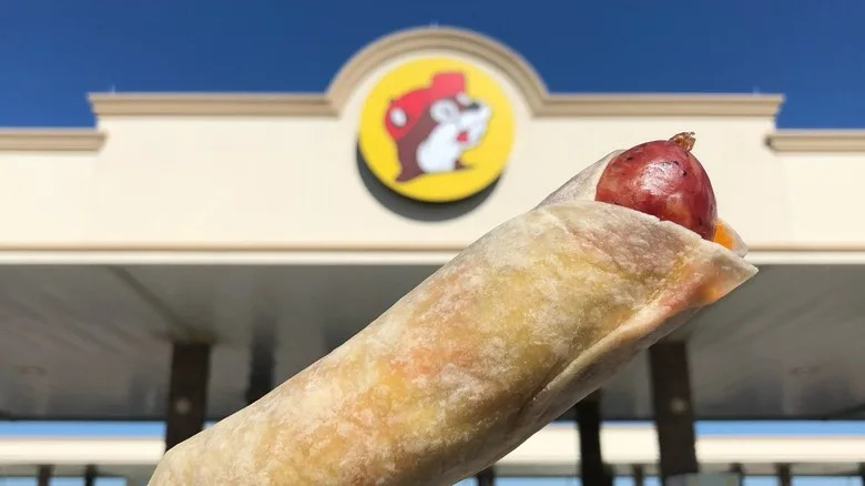 Sausage on a stick in front of Buc-ee's sign