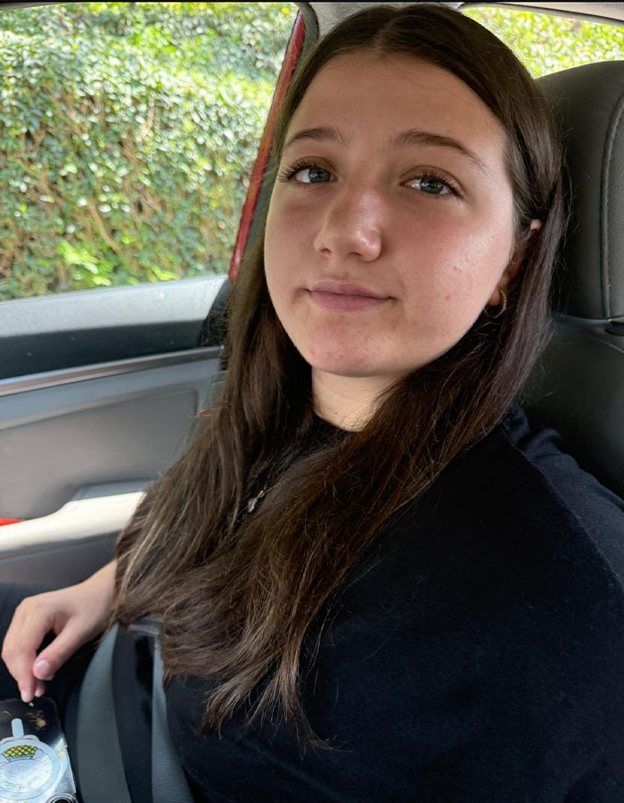 Teen driver sitting in car seatbelted, looking at camera with a neutral expression, related to fatal hit-and-run case.