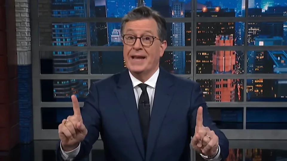  Stephen Colbert pointing up with both index fingers while giving monologue on The Late Show. 