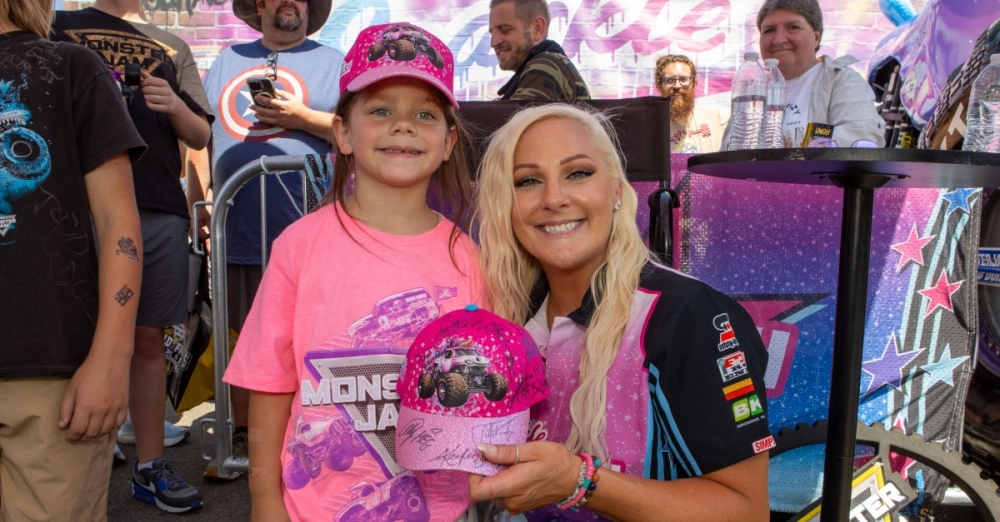 a woman and a girl pose with a Monster Jam hat