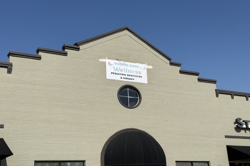 The exterior of an unfinished dental office with a "coming soon" sign.